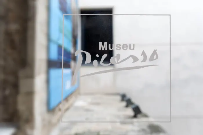 Se ve un letrero con el texto “Museu Picasso” sobre una pared en un entorno urbano.