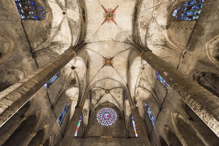 Vista interior de una iglesia con bóveda de piedra y vitrales en las ventanas.