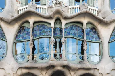 Se ve una fachada modernista con arcos de piedra, columnas y ventanas con mosaicos azules.