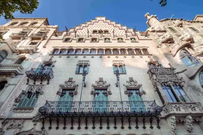 Se ve una fachada de estilo modernista con balcones y una figura escultórica en la parte superior.