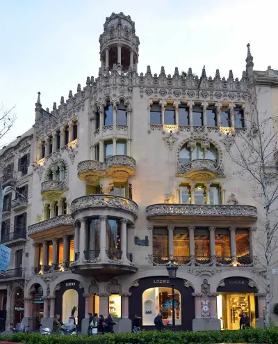 Se ve una fachada modernista con balcones y arcos decorativos sobre la calle.