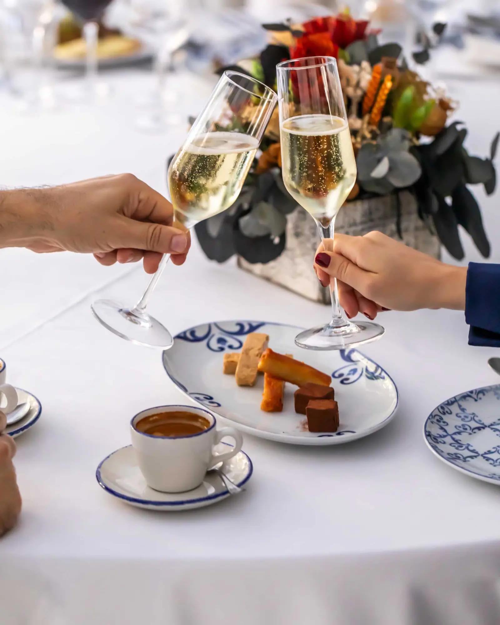 Diverses persones brinden amb copes de vi sobre una taula amb aperitius i tasses.