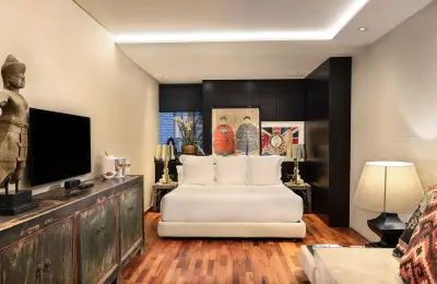 Una habitación de hotel elegante y moderna con mobiliario de tonos neutros y detalles decorativos sofisticados, diseñada para ofrecer comodidad y estilo a los huéspedes.