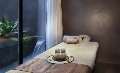 Imagen que muestra un spa con una piscina de agua clara y rodeada de vegetación tropical, creando un ambiente relajante y natural.