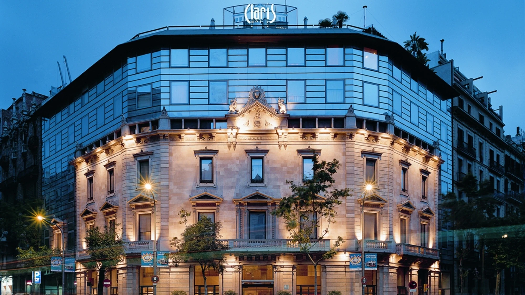La imagen muestra la fachada del Hotel Claris Gran Lujo en Barcelona con un diseño moderno y elegante, con detalles en tonos neutros y una entrada acogedora.