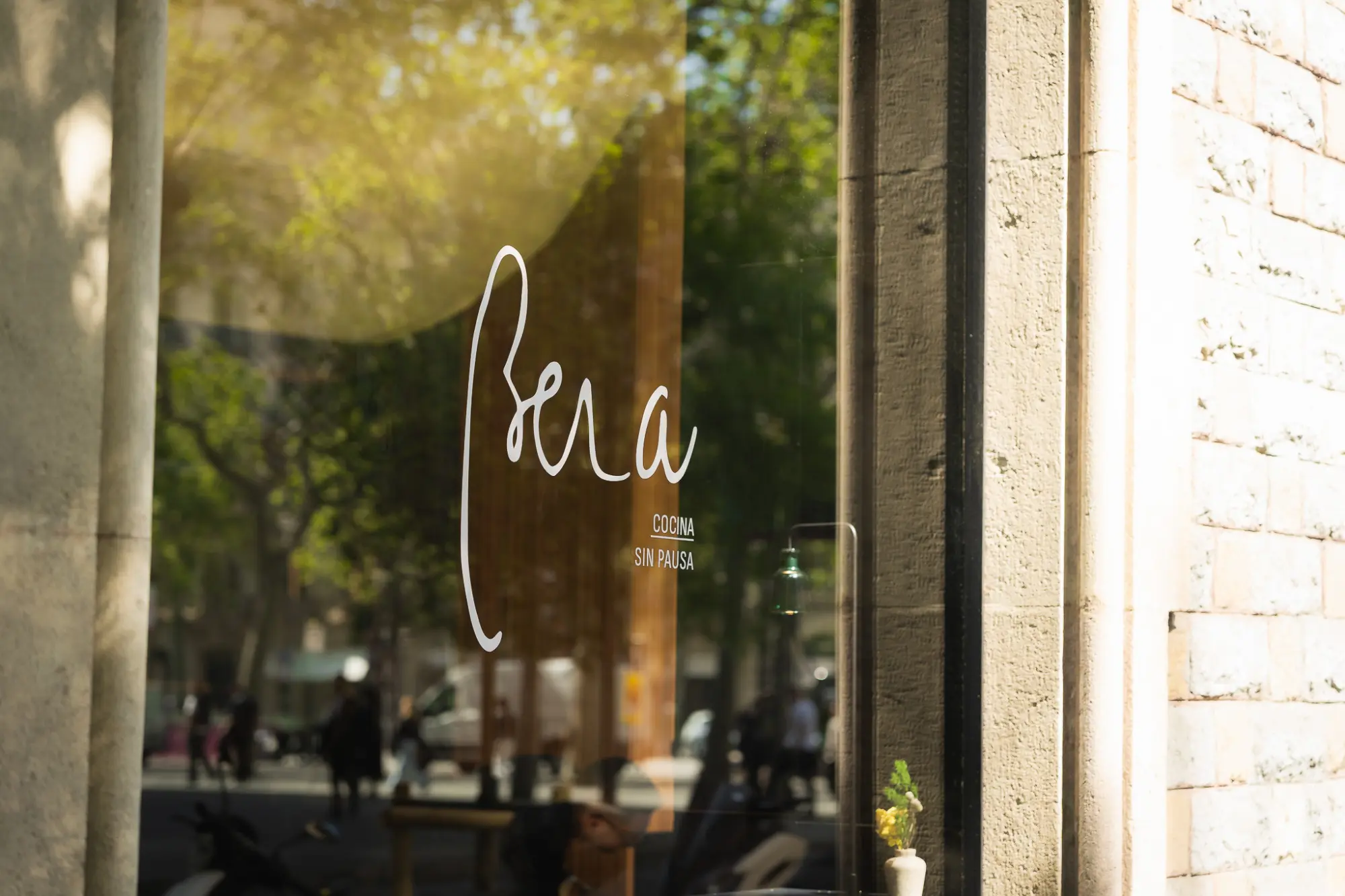 Se ve un ventanal junto a un muro de ladrillo con una mesa y sillas al exterior.