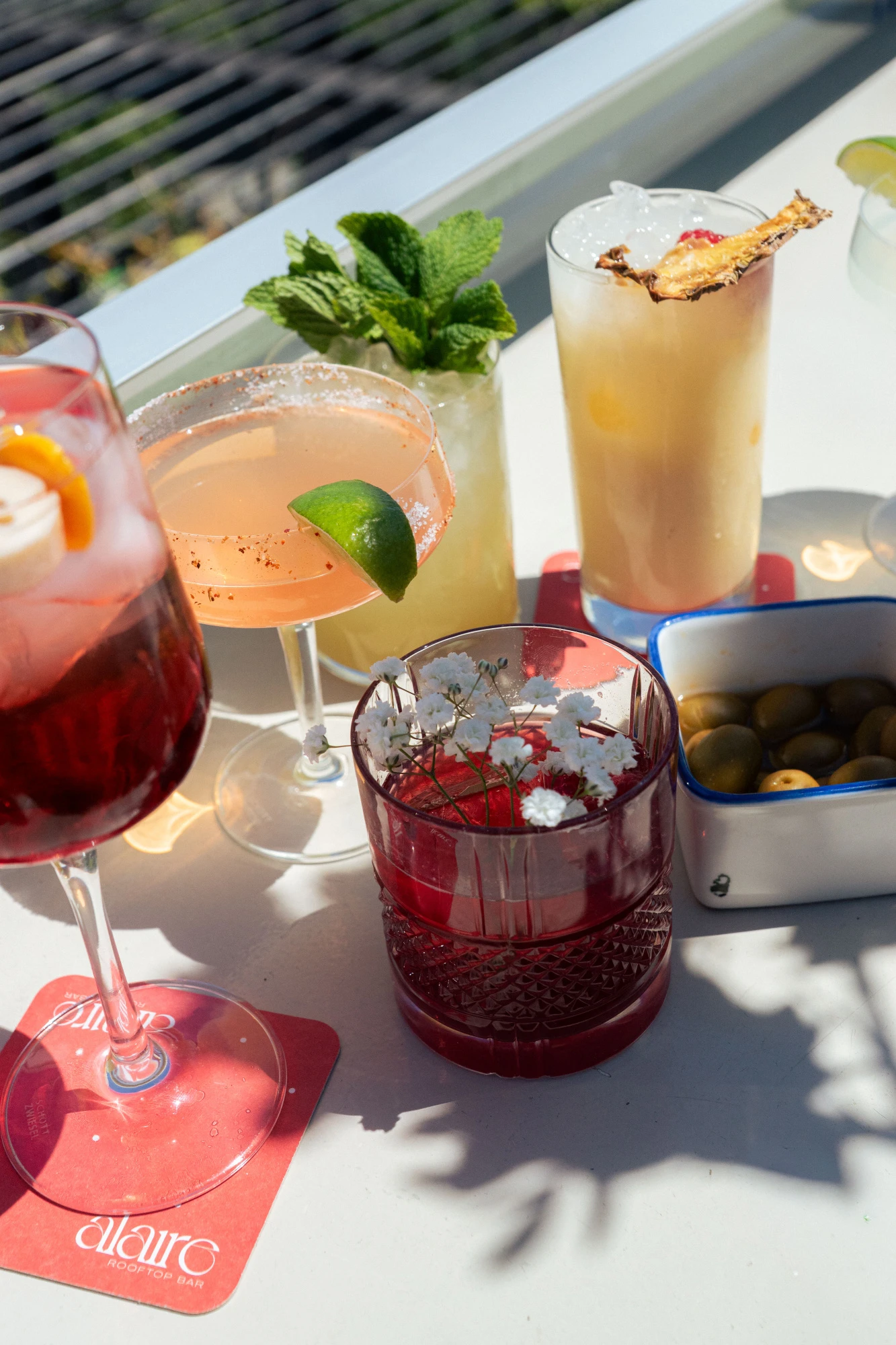 Se ven varios cócteles servidos en vasos sobre una mesa al aire libre.