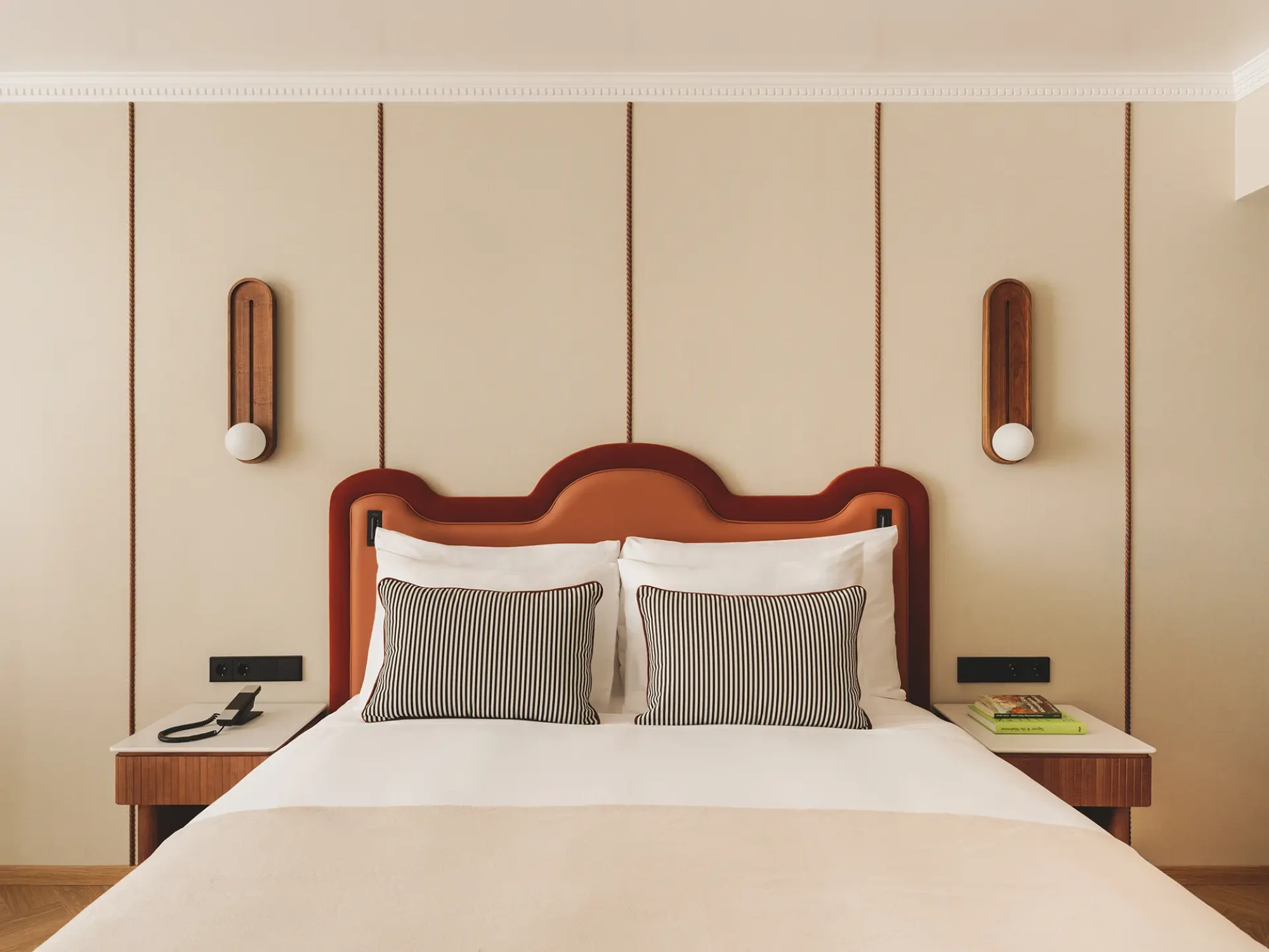 Se ve una cama doble con ropa de cama blanca y almohadas a rayas en un dormitorio.
