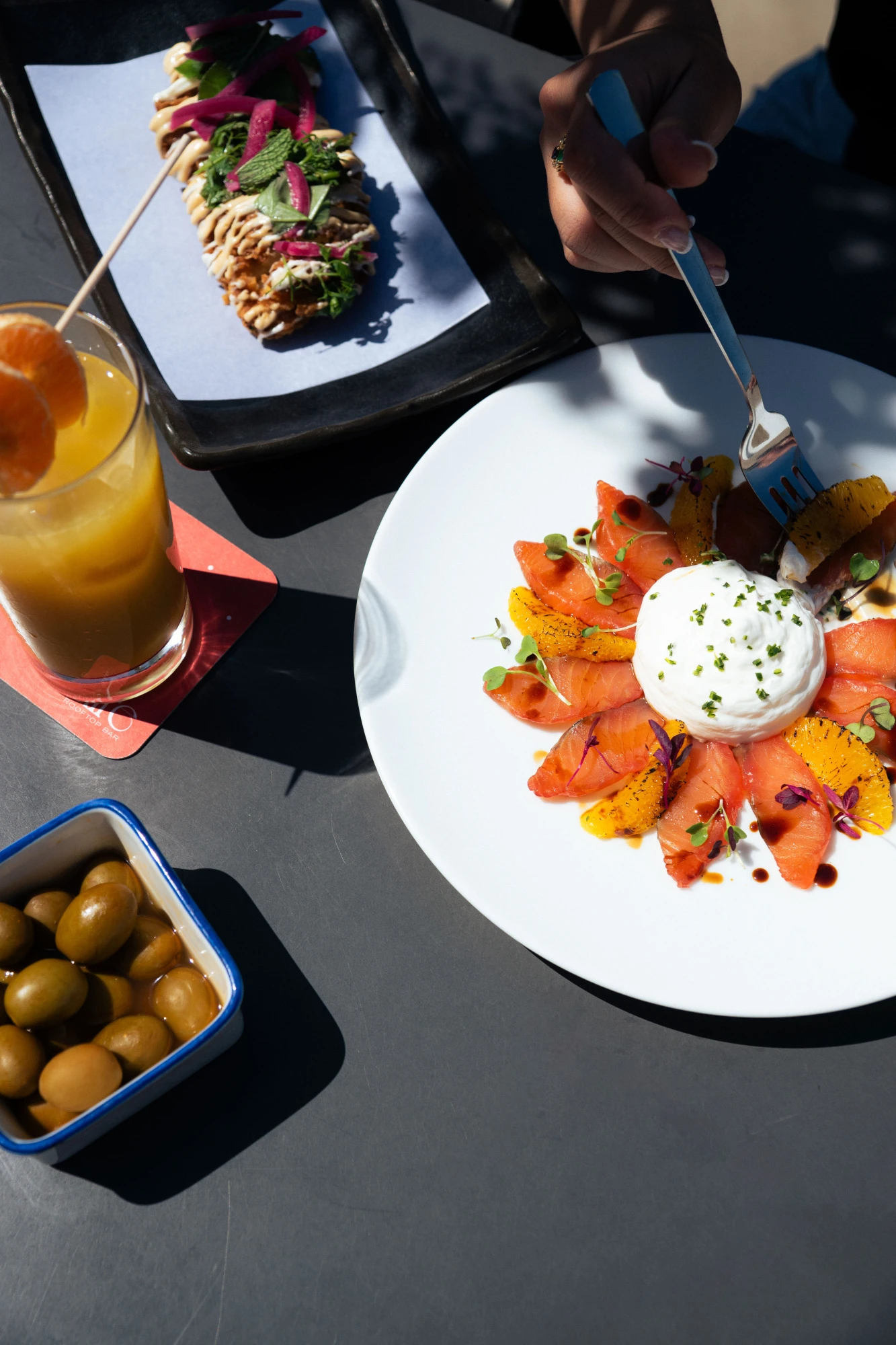 Sirven un plato con ensalada y queso mientras se prepara en una mesa al aire libre.