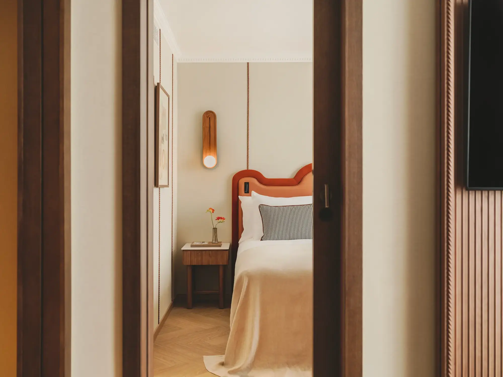 Se ve una cama con ropa de cama blanca y una mesita de noche en un dormitorio de suite.