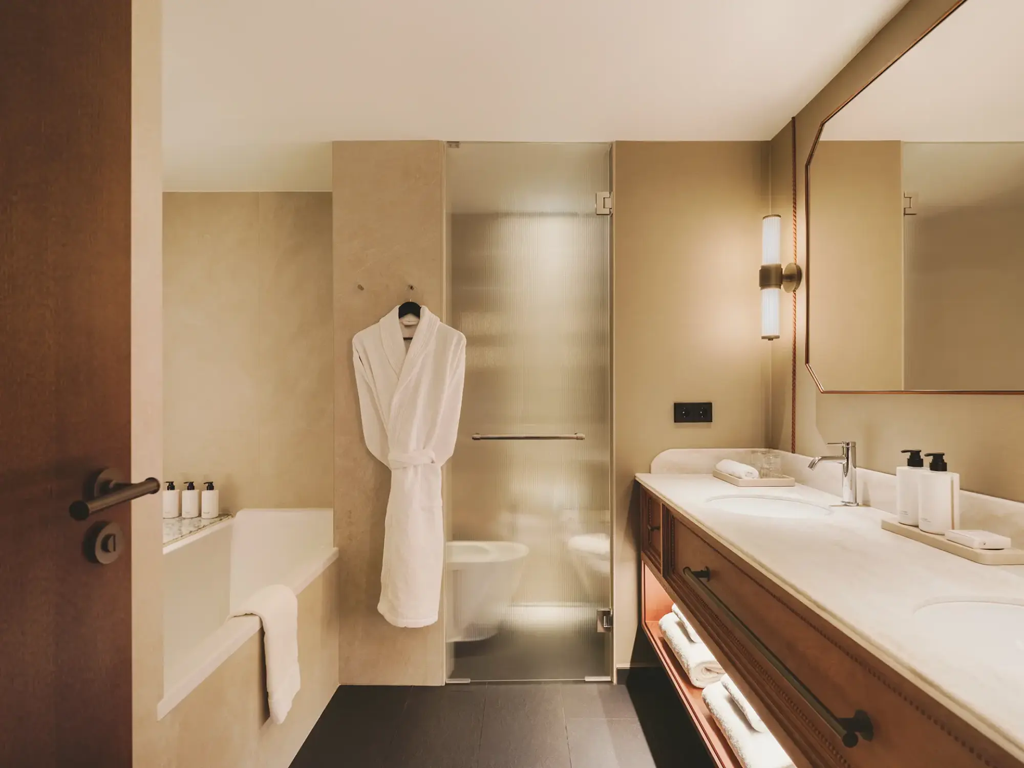 Se ve un baño con lavabo doble, espejo, ducha y toallas dobladas.