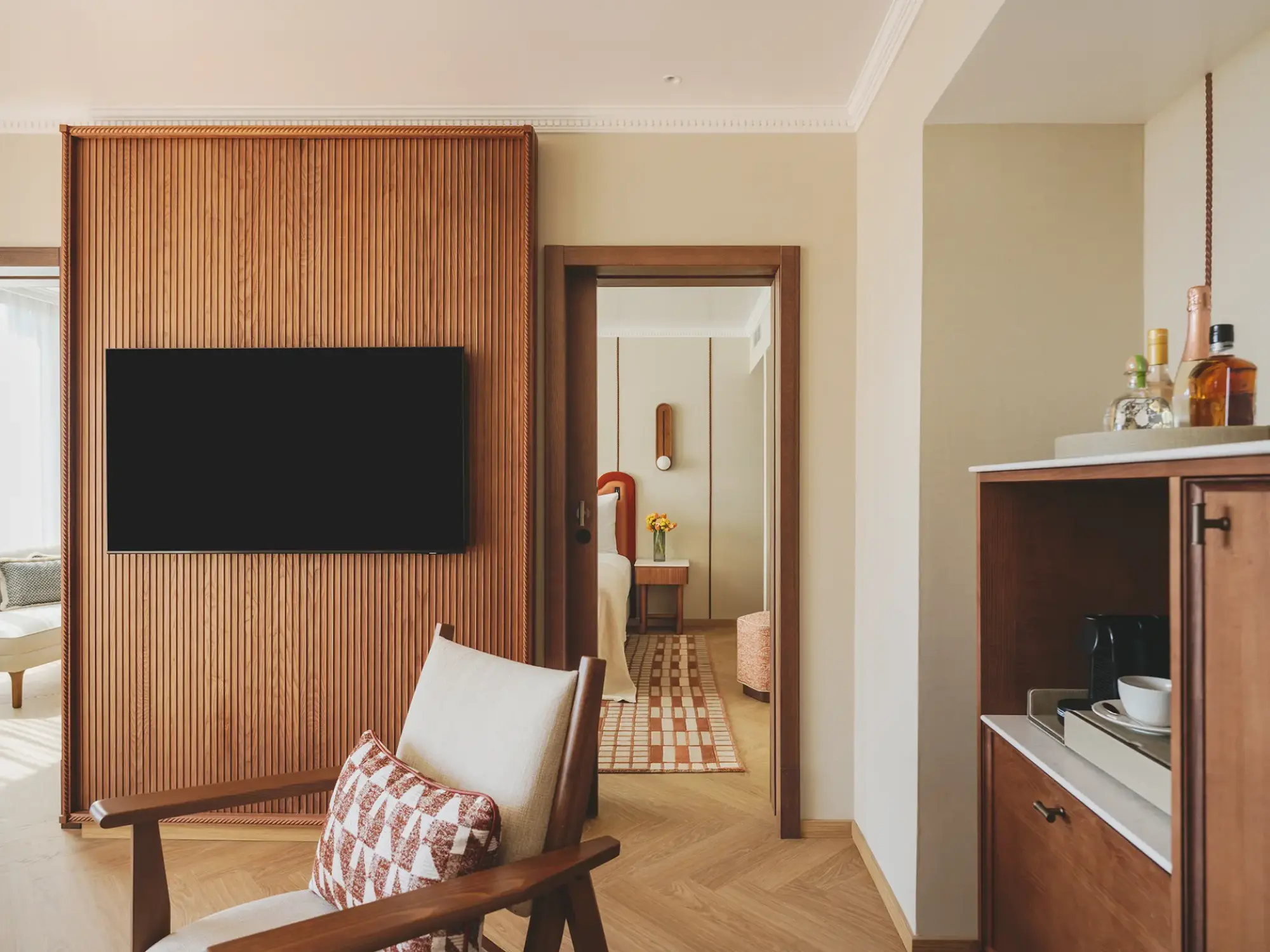 Se ve una suite con una cama, un televisor y una zona de paso hacia el interior.