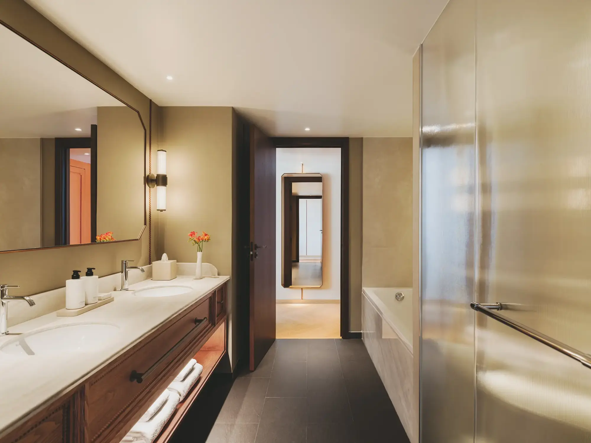 El baño muestra dos lavabos sobre encimera de madera y una ducha con mampara de vidrio.