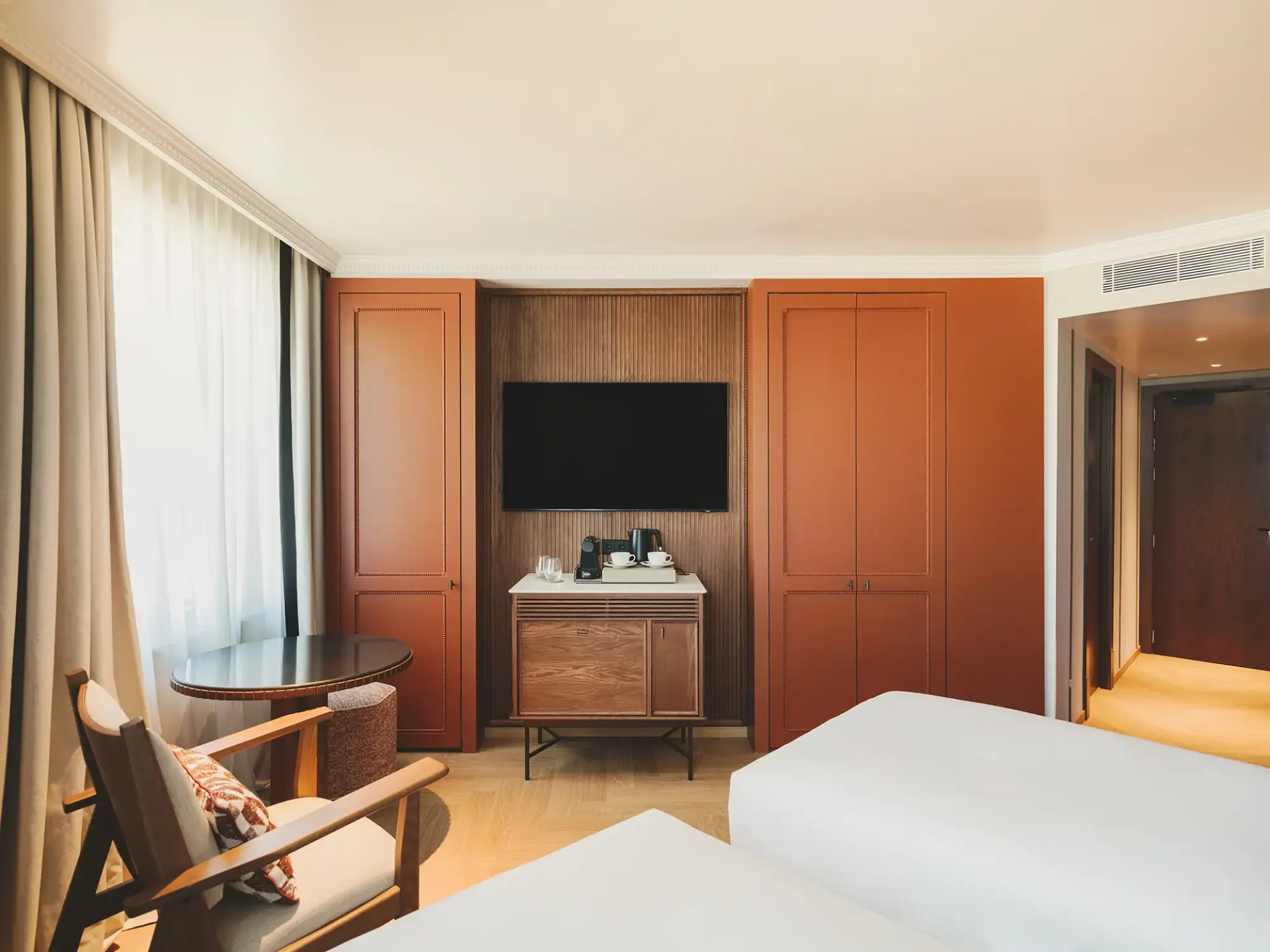 Se ve una cama doble, un tocador con espejo y un televisor en una habitación con armarios de madera.