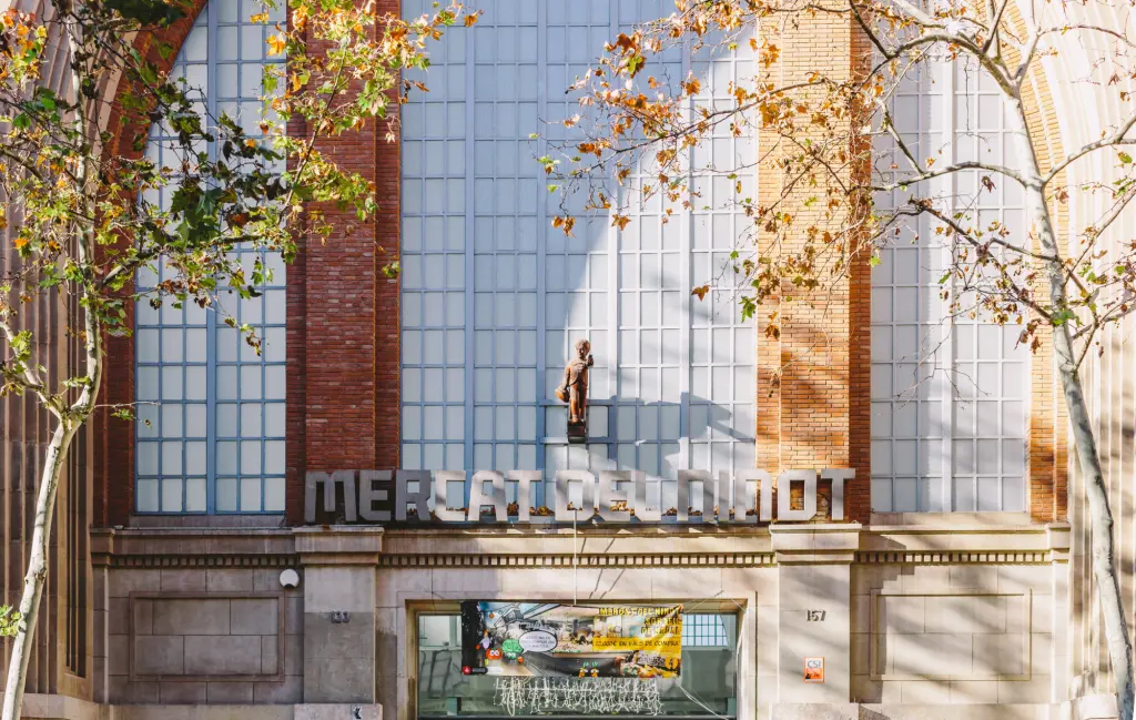 Se ve la fachada urbana de un edificio con un letrero que dice “mercat del ninot”.