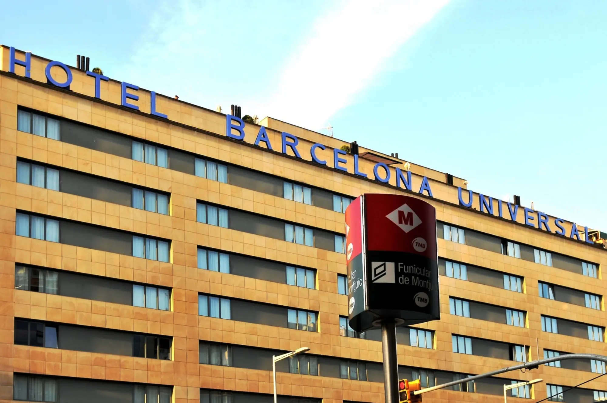 El edificio del hotel muestra el rótulo “HOTEL BARCELONA UNIVERSAL” sobre la fachada de ladrillo.