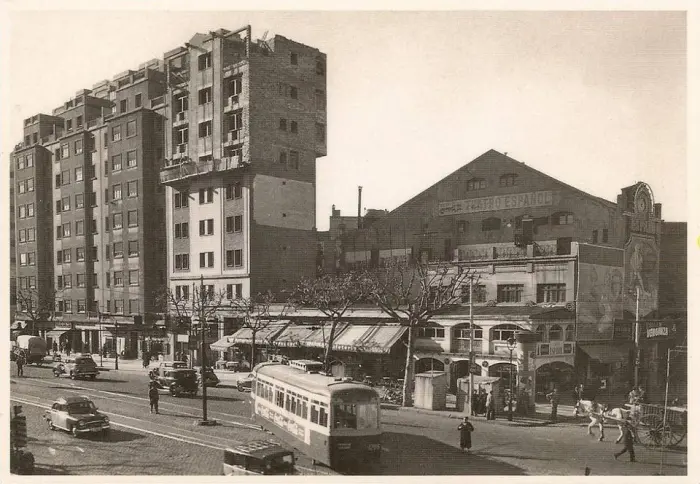 Ilustración en blanco y negro de un entorno urbano con edificios, coches y una parada de tranvía.