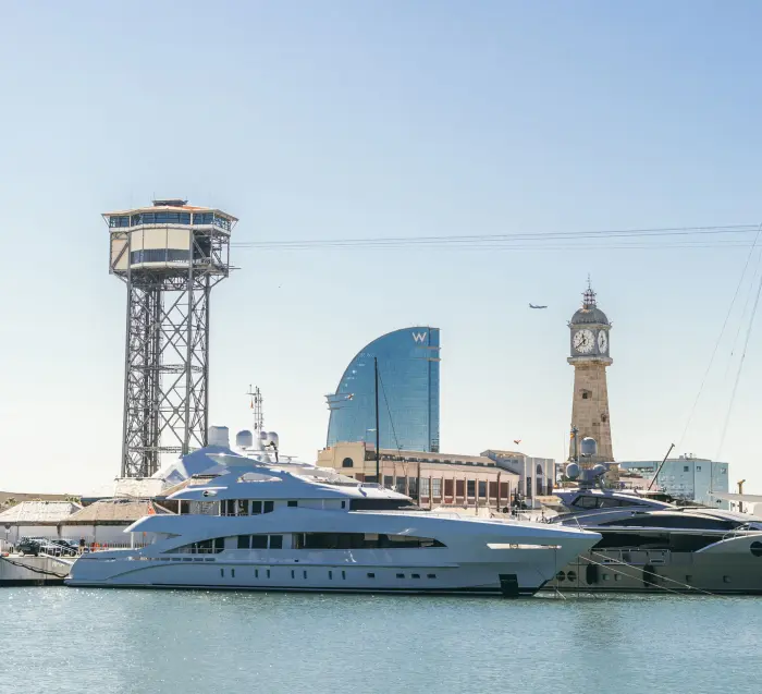 Vista de un puerto con barcos amarrados junto al agua y edificios al fondo.