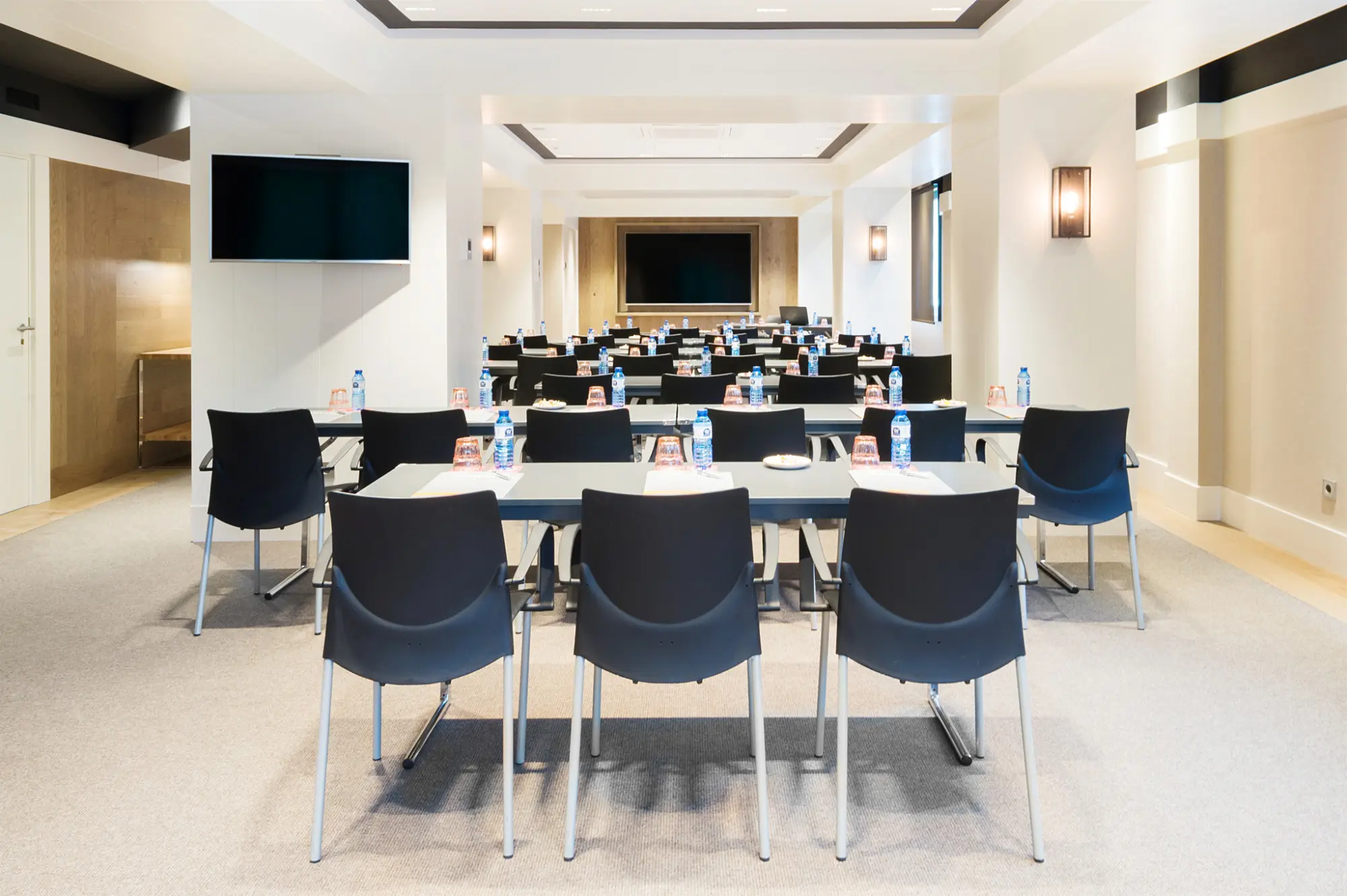 A bright room with rectangular tables and chairs arranged around them for meetings.